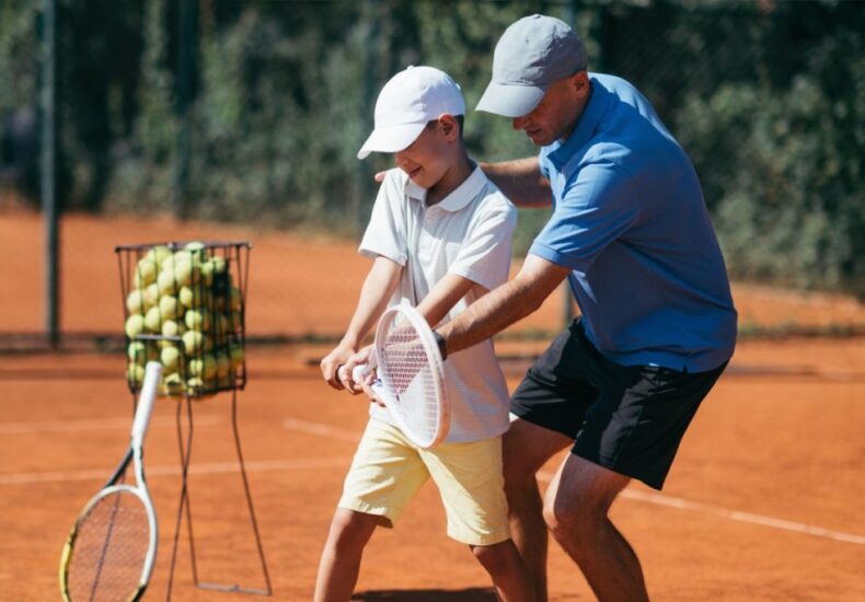 Antrenor Ionuț Jianu explicând un exercițiu unui copil în timpul unui antrenament de tenis la Baza Olimpia din Sectorul 3 București.
