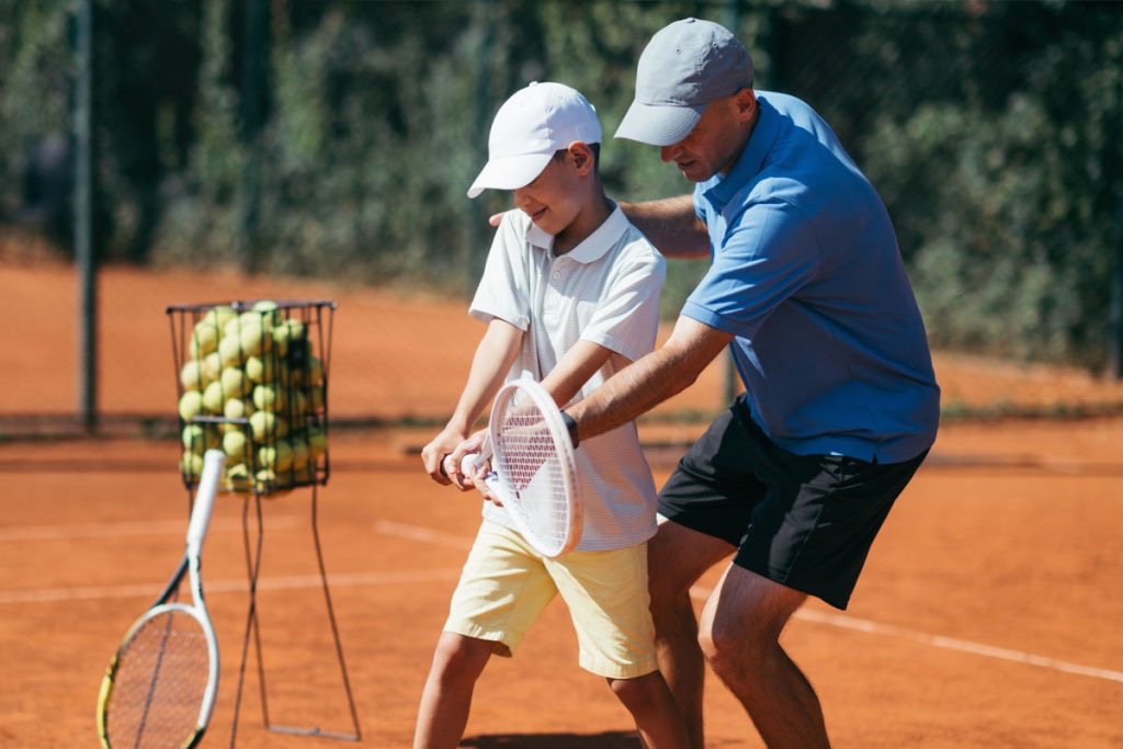 Antrenor Ionuț Jianu explicând un exercițiu unui copil în timpul unui antrenament de tenis la Baza Olimpia din Sectorul 3 București.